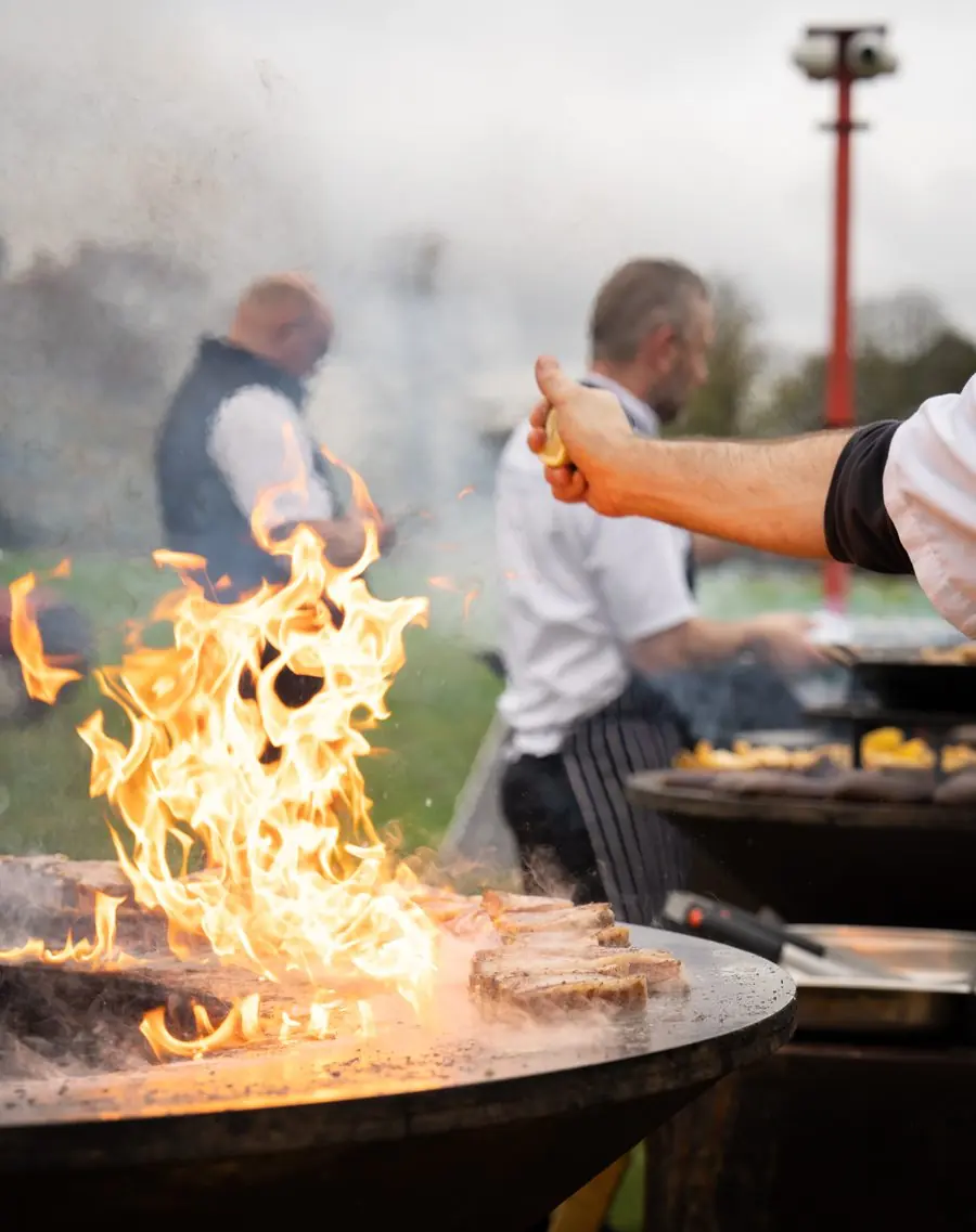 Chefs cooking on open flame grill